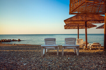 a couple of sun loungers with an umbrella on the background of the sea at dawn .copy space