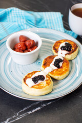 Sweet cheese pancakes on plate served strawberries. Syrniki, ricotta fritters, curd fritters