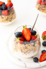 Homemade granola with almonds in a glass with yogurt, fresh strawberries and blueberries, delicious healthy breakfast