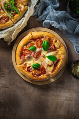 Two hot juicy fresh pizzas with bacon and cheese are on a wooden table