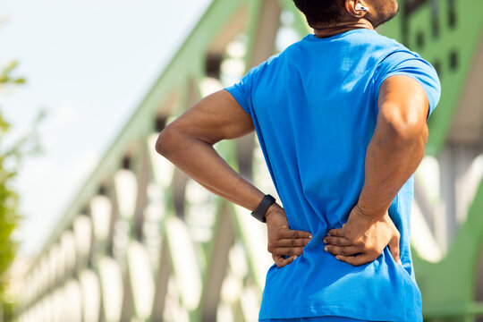 Sports injury. Young sportsman suffers from lower back pain while exercising
