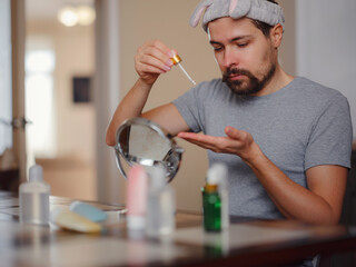 Men's beauty concept. caucAsian guy checking his skin. Skin nutrition. Young man applying organic...
