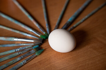 the brushes are laid out in a fan on the table, in center, around the egg, ready for painting, blank for the designer