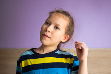 girl child in a striped turtleneck shows joy and happiness because of a cotton stick in the ear, where it became mirror-clear