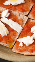 Tostadas de pan con tomate rallado, queso en trozos y aceite