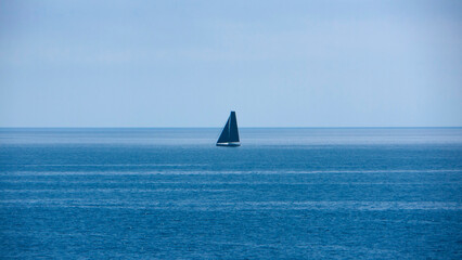 Velero de velas azules en el horizonte de mar mediterraneo © Darío Peña