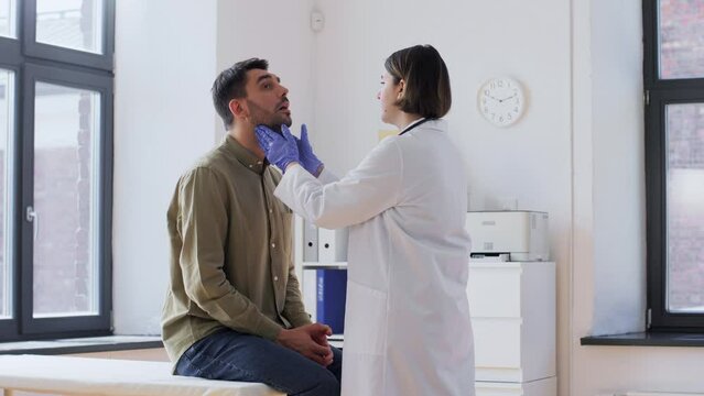 medicine, healthcare and people concept - female doctor checking lymph nodes of male patient at hospital