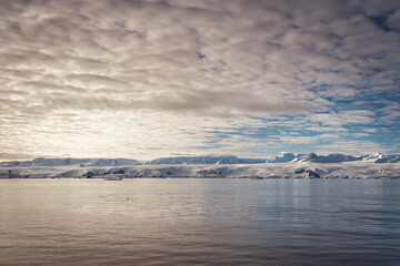 Antarctica mountains and sea. Clouds and blue sky