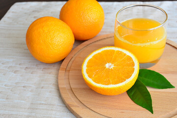 fresh oranges with glass of orange juice on pastel background, close-up
