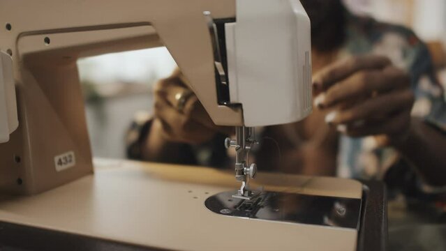 Indian dressmaker threading sewing machine while starting work on new collection in atelier