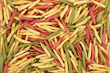 Fusilli pulgiesi Italian healthy tricolor pasta forming an abstract background. Spinach and tomato food green and red colouring on semolina based ingredients and used in traditional cooking. Top view.