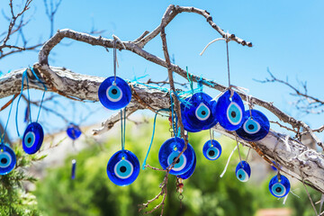Amulets from the evil eye blue glass eyes on the branches of a tree in Cappadocia. A tree with blue...