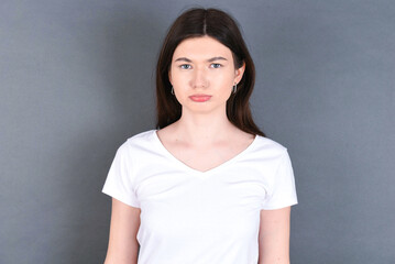 young beautiful Caucasian woman wearing white T-shirt over grey wall crying desperate and depressed with tears on his eyes suffering pain and depression. Sad facial expression and emotion concept.