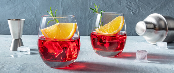 Campari cocktails with fresh oranges, rosemary, a jigger and a shaker, a mixology panorama