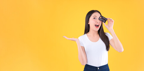 Photo happy positive pretty asian woman smile showing, presenting credit card for payment or paying online business payment credit card for confident money and financial concepts yellow background.