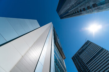 Fototapeta na wymiar Modern glass buildings in the city on a sunny clear day with a blue sky, photo from bottom to top