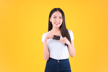 Naklejka premium Photo happy positive pretty asian woman smile showing, presenting credit card for payment or paying online business payment credit card for confident money and financial concepts yellow background.