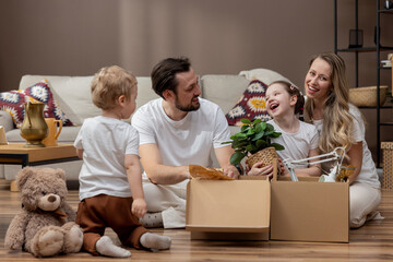 Caucasian family, parents son and daughter unpack boxes and move into new home. Adults rejoice at change of location happiness shared joy.