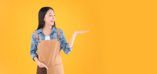 pretty asian female smile coffee freelancer own shop ands point up and pose to copy space yellow background.