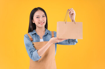 Fototapeta na wymiar pretty asian female smile freelancer own shop show paper bags to customers buy products yellow background.