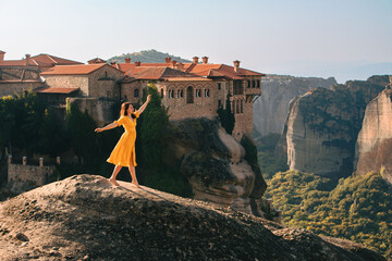 happy woman in yellow dress traveler meteora monastery on the background - obrazy, fototapety, plakaty