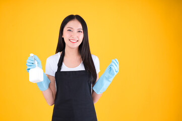 attractive asian female smile wearing black apron her hands with blue rubber gloves holding a white spray bottle poses cleaning.