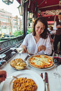 picture of woman in restaurant eating pizza drinking wine