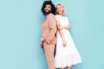 Smiling beautiful woman and her handsome boyfriend. Sexy cheerful multiracial family having tender moments on blue background in studio. Multiethnic models hugging. Embracing each other.Love concept
