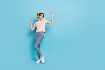 Full length photo of charming pretty woman wear beige t-shirt headphones dancing empty space isolated blue color background