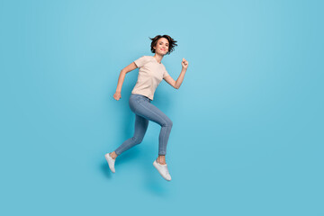 Fototapeta na wymiar Full length photo of cute charming woman wear beige t-shirt hurrying jumping high isolated blue color background