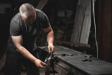 A worker prepares a woodworking machine for work in his home workshop. Making metal products with your own hands