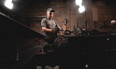 Fototapeta na wymiar A man works with an angle grinder in his home workshop. Making metal products with your own hands