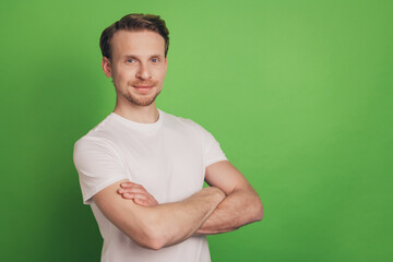 Fototapeta premium Cheerful positive masculine strong attractive man folded arms isolated on green color background
