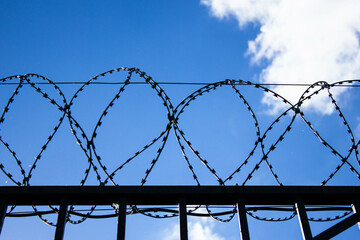 Barbed wire on a high fence against the sky. Barbed wire on the border of the country. Security of...