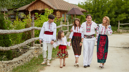Full length image Happy family with kids in traditional romanian clothes in a countryside. Father, mother, son and daughters walking outside.