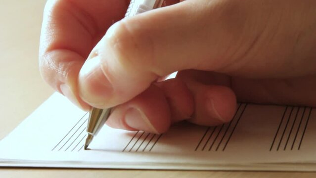 Handwritten notes and female hand holding a pen and writing notes, composing music, selective focus