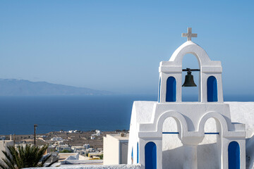 Blue and white colored Greek orthodox church, bells and cross roof, during a sunny summer day - obrazy, fototapety, plakaty