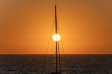 Sunset with a round and orange sun in Santorini, in the Greek islands
