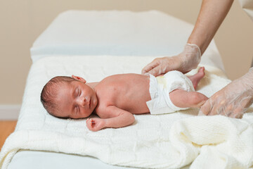 Physical therapist performing an evaluation of the lower extremities in a newborn baby.