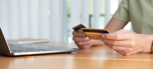 Online shopping. Young woman holding credit card and using laptop at home. African american girl working on computer at cafe. Business, e-commerce, internet banking, finance, freelance concept