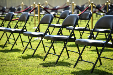 Rows of black chairs on green turf before a ceremony