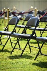 Rows of black chairs on green turf before a ceremony