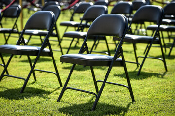 Rows of black chairs on green turf before a ceremony