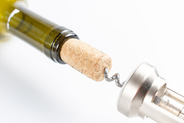 Close-up of a corkscrew opening a bottle of wine. The cork is pierced by the black metal spiral of...