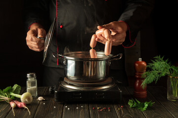 The chef cooks Vienna sausage in a saucepan. Working environment in the kitchen. Delicious breakfast or dinner