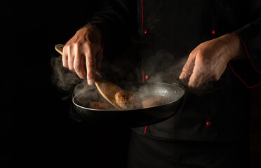 Meat steak on barbecue grill on wooden tool - spatula handle. Cooking cutlets from beef or pork in a pan in the hands of a chef.