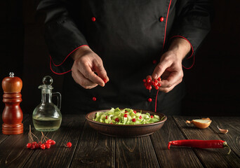 The chef prepares a salad for breakfast or lunch in the kitchen from fresh cabbage and viburnum for diet