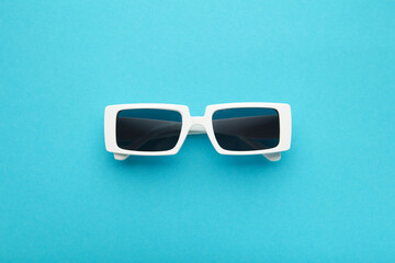 White sunglasses on blue background, top view, flat lay, minimalistic concept of summer, vacation.