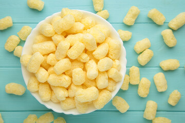 Sweet corn sticks in bowl on blue background