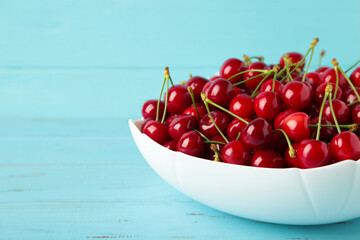 Fresh sweet cherries bowl on blue wooden background, top view
